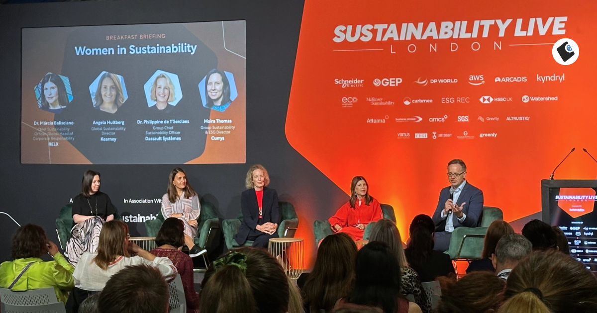 A panel discussion at Sustainability Live London titled "Women in Sustainability." Four female leaders—Dr. Márcia Balisciano (RELX), Angela Hultberg (Kearney), Dr. Philippine de T’Serclaes (Dassault Systèmes), and Moira Thomas (Currys)—are featured on the event screen. They are seated on stage alongside a male moderator, engaging with an audience. The backdrop displays logos of event partners and sponsors, with a strong orange and black color scheme.