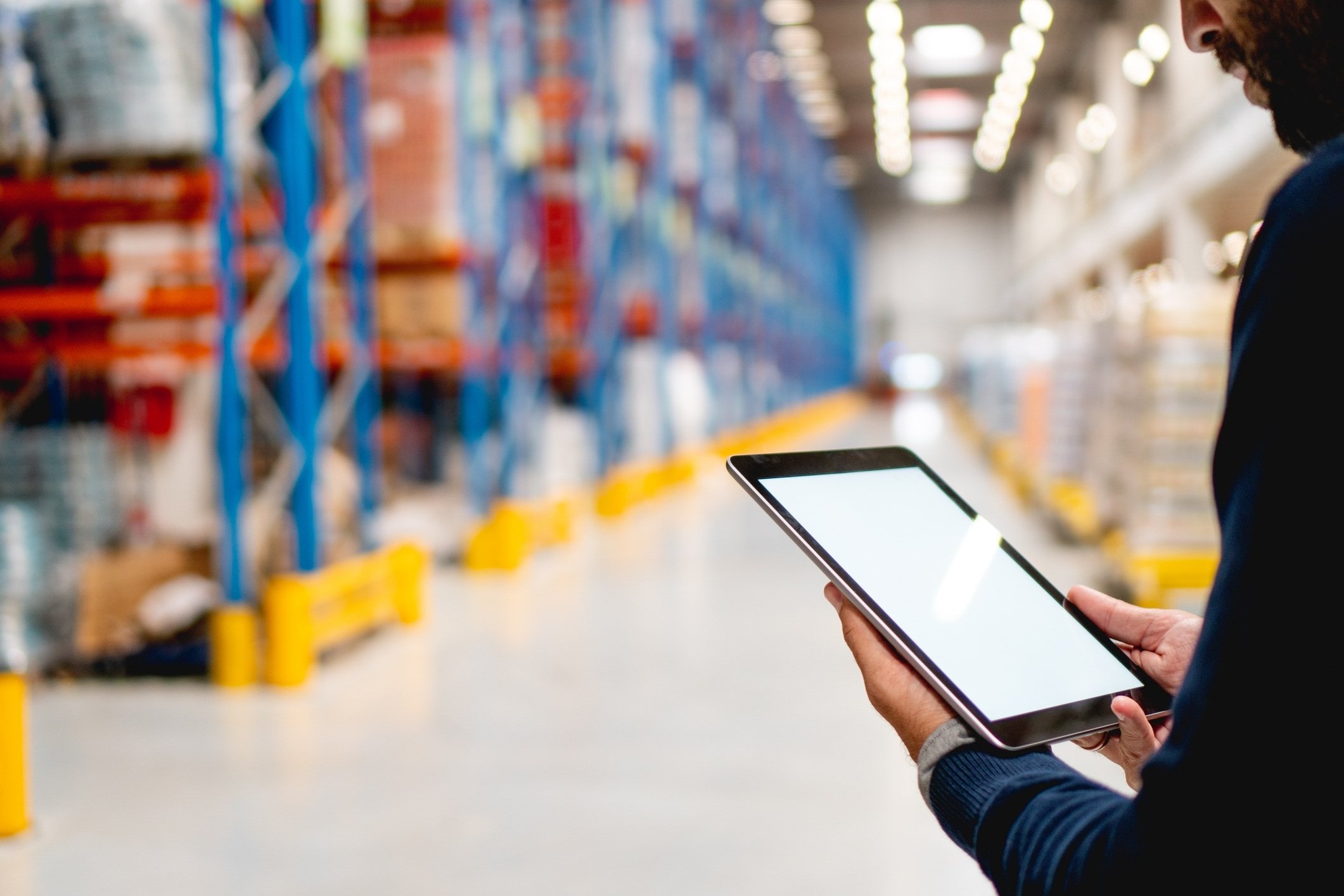 Person using a tablet to analyse stock in a warehouse.